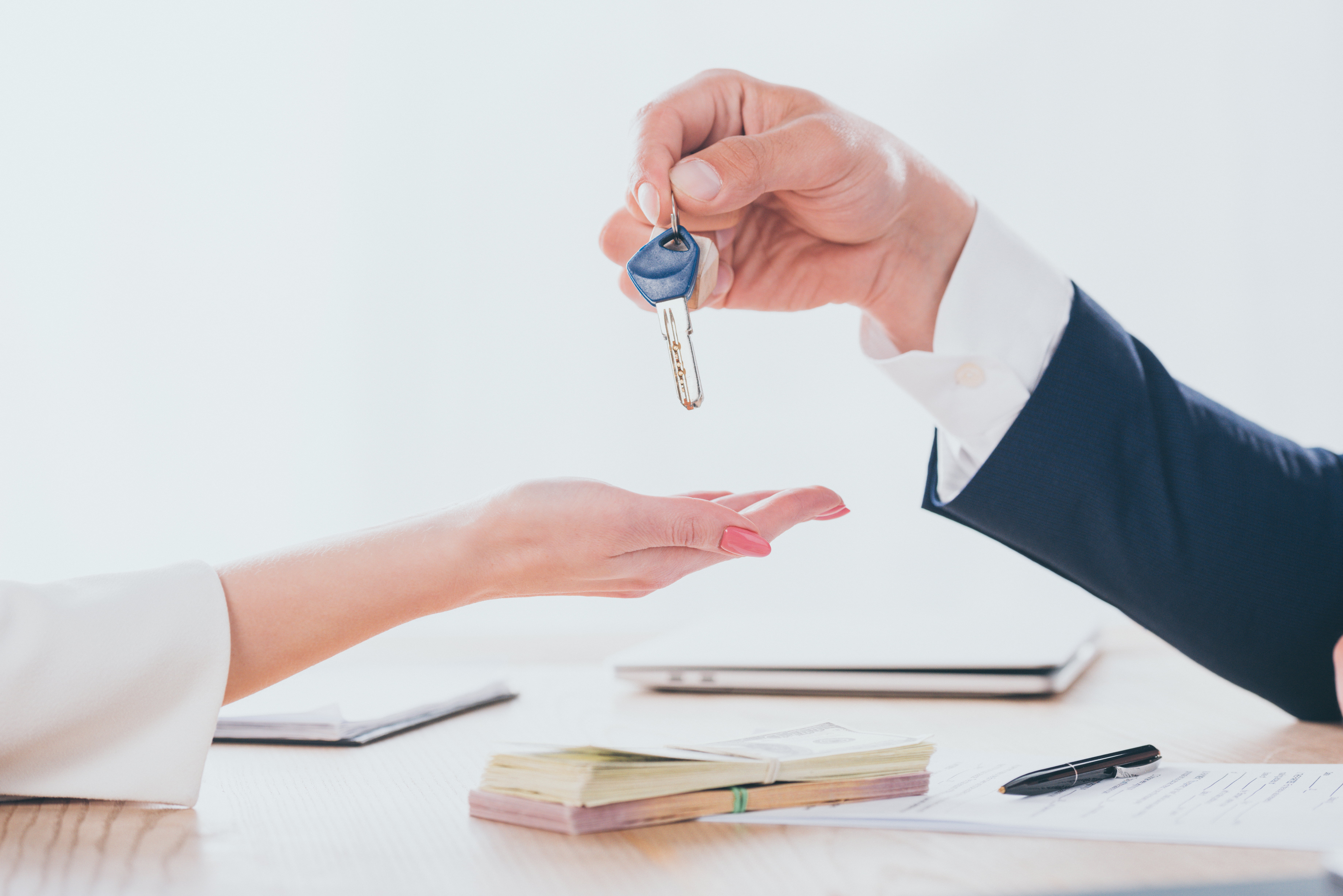 cropped shot of car dealer giving car keys to client in office